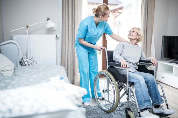 Pflegekraft kümmert sich um Frau im Rollstuhl