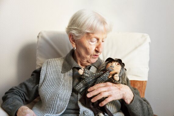 Seniorin mit Puppe im Arm