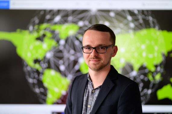 Mann mit Brille vor einer vernetzten Weltkarte